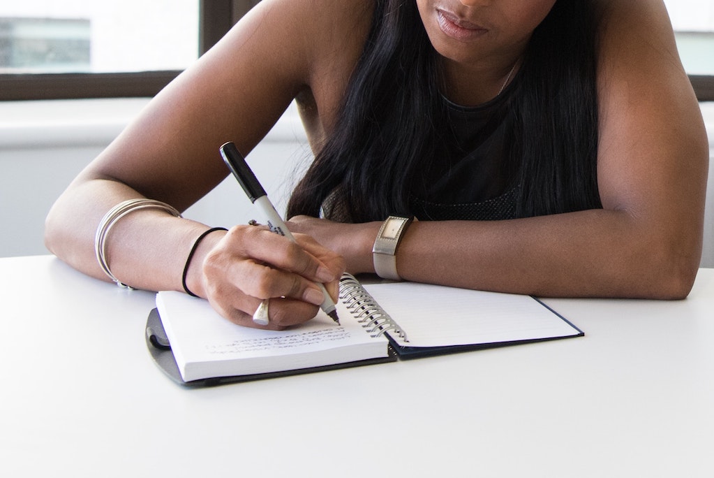 A woman takes notes by hand in an office setting