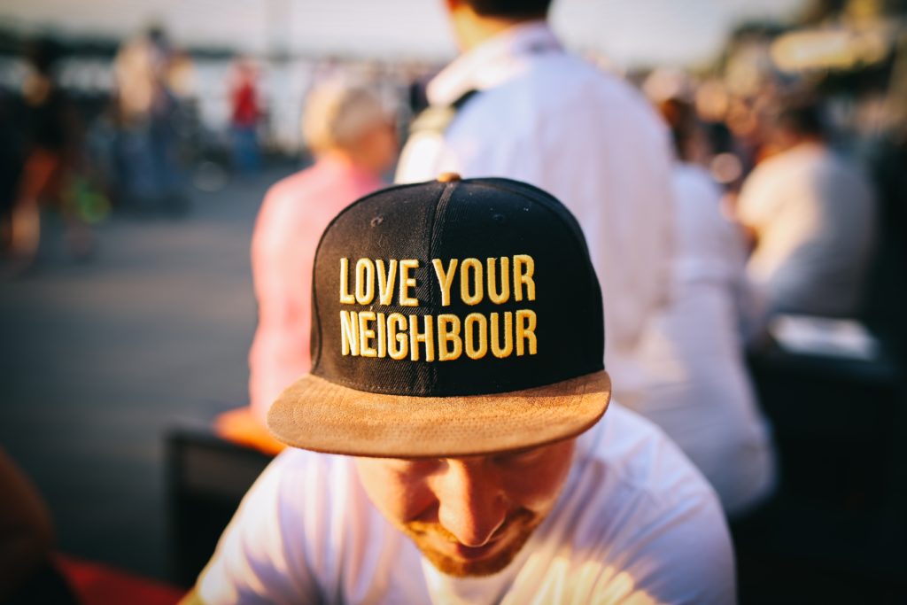 Person in yellow and black "love your neighbor" hat