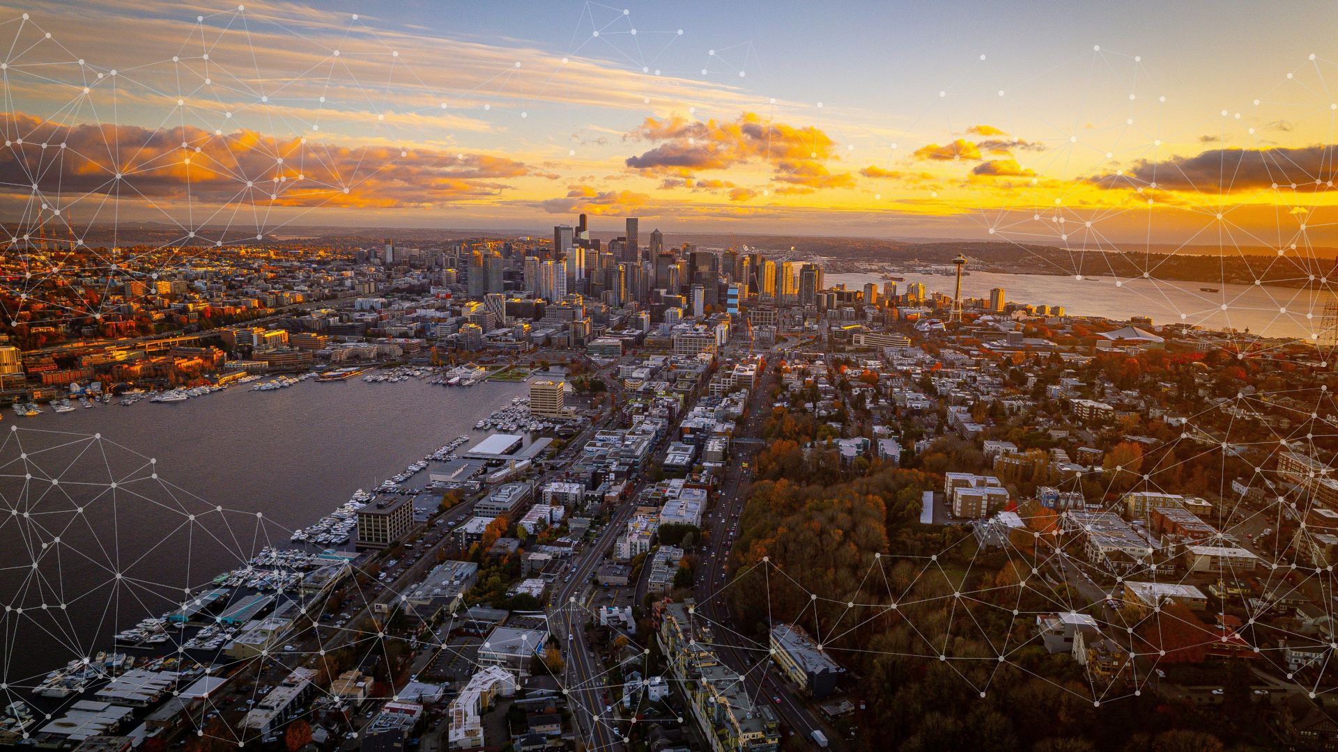 An aerial shot over Seattle from the East Queen Anne area, overlooking Lake Union, Lower Queen Anne, with the Downtown Seattle skyline and Elliott Bay in the distance at Sunset