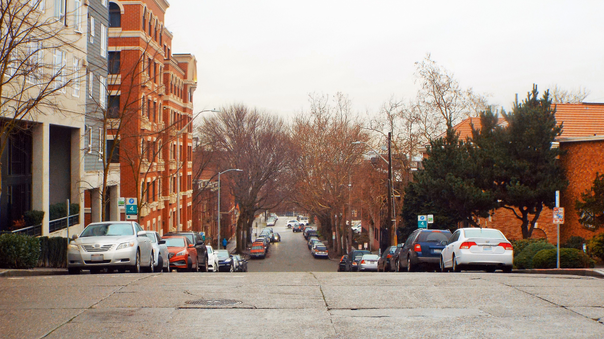 A view looking down a Seattle city street with cars parked on both sides